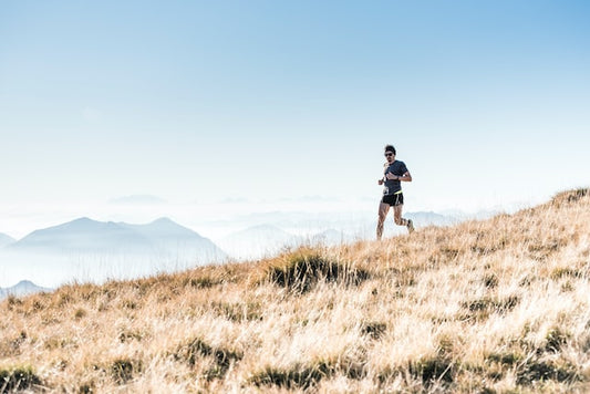 Trail runner running down hill, blue sky in background